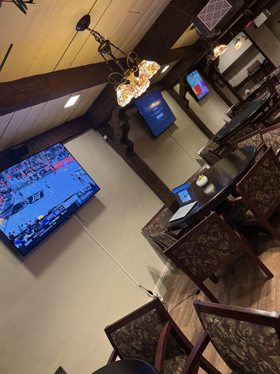 TVs showing sports above cozy tables and chairs in the Embers Vine cigar lounge
